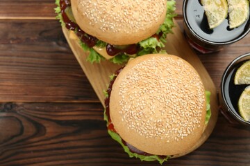 Delicious cheeseburgers and drinks on wooden table, top view. Space for text