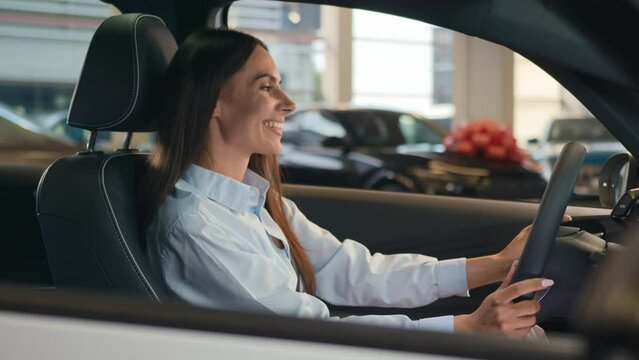 Happy smiling Caucasian female driver inside car choosing automobile in salon woman girl lady smile enjoy sitting in luxury auto buying new transport buy vehicle rent service rental test drive choose