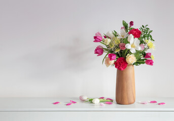 beautiful flowers  in vase on shelf  on background white wall