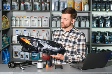 man holds automotive headlight in auto parts store