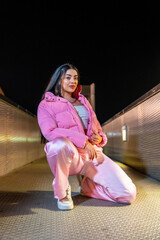 Hip hop dancer in pink clothes kneeling outdoors at night