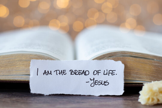 I am the bread of life-Jesus Christ, handwritten verse and open holy bible book with bokeh light background. Close-up. Christian spiritual food, belief in the Son of God, biblical concept.
