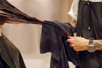 Close up of hairdresser is wrapping the wet hair of woman in towel after washing at beauty salon