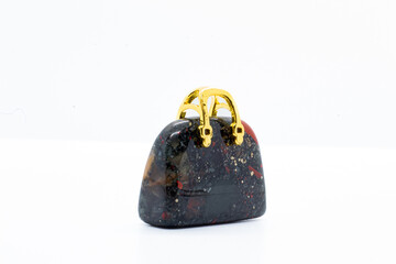 Blood stone Chalcedony, Heliotrope opaque silicate mineral, Crystal carving Bag with a gold metal handle isolated on white background surface 