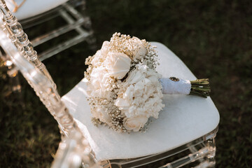Wedding details. A bouquet of roses and gypsophila on a white chair