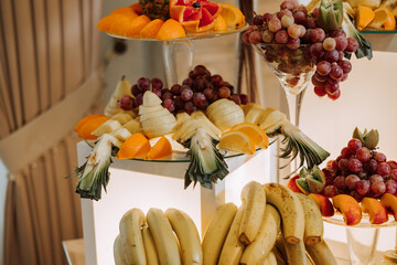 A banquet table full of fruits and berries, an assortment of sweets. Bananas, grapes, pineapples. Fruit compositions for the holiday.