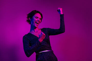 Photo portrait of attractive young woman raise fists champion dressed stylish overall clothes isolated on neon light pink color background