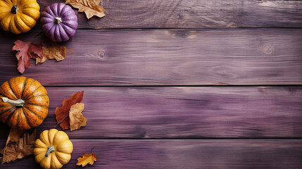 A group of pumpkins with dried autumn leaves and twigs, on a purple color wood boards