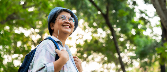 Portrait of Asian mature woman in a hat with backpack behind her back, an Asia active senior woman...