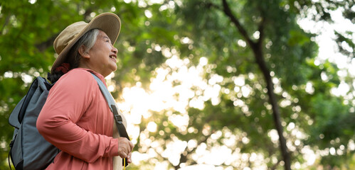 Portrait of Asian mature woman in a hat with backpack behind her back, an Asia active senior woman...