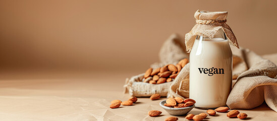 Banner with a glass bottle of almond milk with the inscription VEGAN on a beige background with...