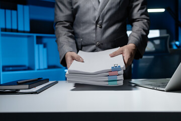 An employee held a large pile of documents in his hand, Large piles of work documents on desks are...
