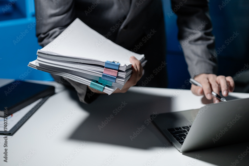 Sticker Employee checking important details of document on laptop, Documents were stacked on the desk, A businessman is sending various information via email while holding a large stack of documents.