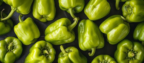 A stack of fresh green peppers, a staple food and natural produce, sits on a table. These vegetables are a local, whole food ingredient