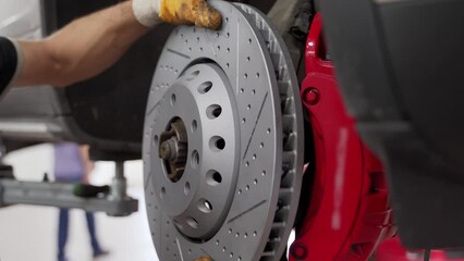 Auto mechanic installs new brake disc, caliper on vehicle. Car repair service procedure, maintenance workshop. Technician replaces brakes, pads, checks rotor. Garage safety inspection process.