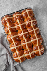 Freshly baked Easter hot cross buns on a baking tray on a gray concrete background. Top view.