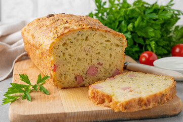 Zucchini bread with cheese, ham and fresh herbs on a wooden board on a gray background. Healthy food.