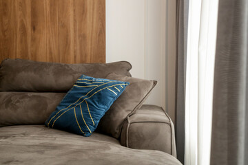 Grey comfortable sofa with blue cushion next to the big window with lot of natural sunlights	