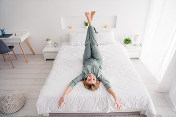 Full body size photo of positive blonde lady raised hands up when lying down white laundry bedroom...