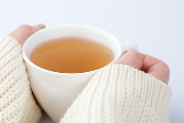 cup of tea with a knitted sweater on a female hand.