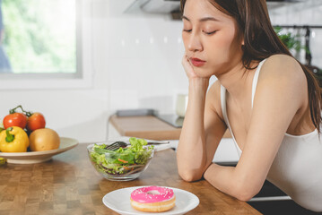 Woman on dieting for good health concept. female choosing between doughnut and salad for good...