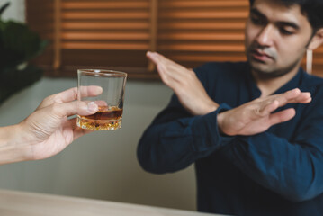 Drunk men deny drinking more glass of whisky by pushing away.