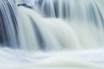 Winter landscape of the Rabbit River Cascade framed by ice and captured with motion blur, Michigan, USA