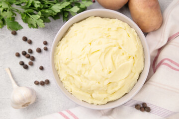 Bowl of tasty mashed potato, parsley,  and pepper on grey marble table