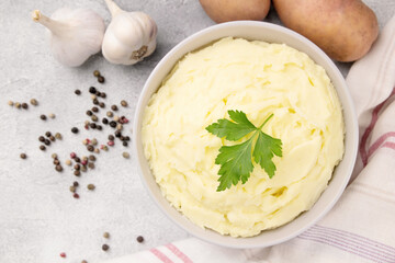 Bowl of tasty mashed potato, parsley,  and pepper on grey marble table