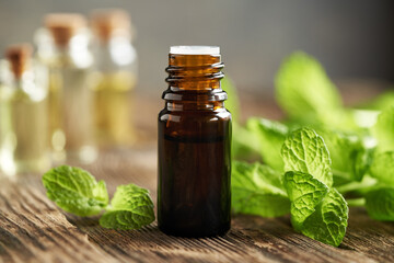 A bottle of aromatherapy essential oil with fresh peppermint leaves