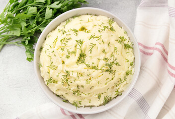 Bowl of tasty mashed potato, parsley,  and pepper on grey marble table