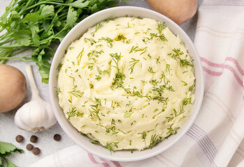 Bowl of tasty mashed potato, parsley,  and pepper on grey marble table