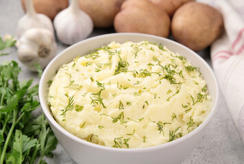 Bowl of tasty mashed potato, parsley,  and pepper on grey marble table
