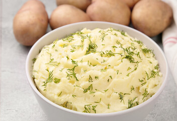 Bowl of tasty mashed potato, parsley,  and pepper on grey marble table