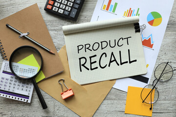 Product Recall stationery and calculator on financial chart. text on notepad page with spiral
