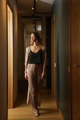 Portrait of young woman in elegant silk loungewear in the apartment