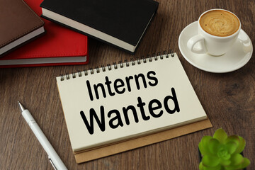 Interns Wanted working environment with notepad and cup of coffee. words