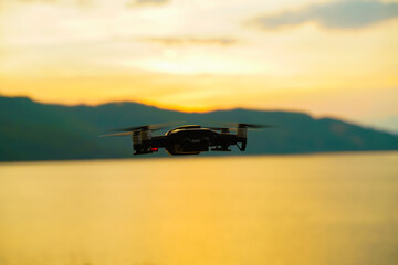 Fototapeta na wymiar Silhouette drone flying over lake sunset