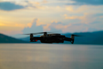 Silhouette drone flying over lake sunset
