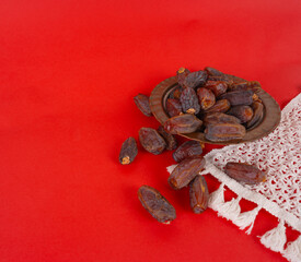 Date fruits, lace veil and copper vintage bowl full of date fruits. Isolated red studio background with copy space text area. Islamic holy month Ramadan concept image.