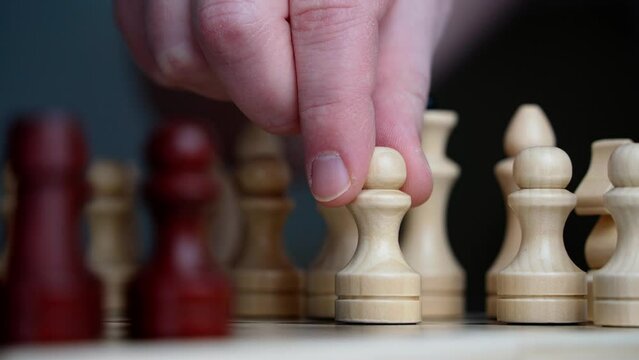 Close-up of a man's hand making a pawn move during a game of chess. Playing chess as a stimulus for the development of intelligence, business planning and strategy.