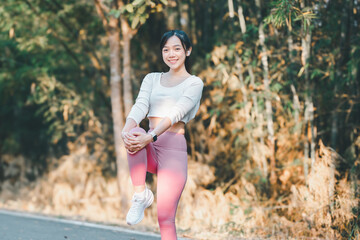 Fitness concept, A fit young woman performs a knee stretch in a sunlit wooded area, wearing casual...