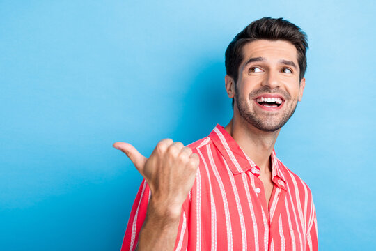 Photo of pleasant satified man with bristle dressed striped shirt look directing at sale empty space isolated on blue color background