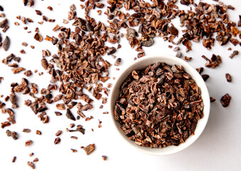 Organic Cacao Nibs in a White Ceramic Bowl. Top View. Vegan Chocolate Ingredient.