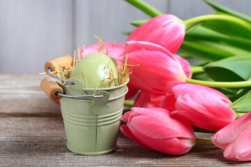 Easter decoration with single egg in a bucket and bouquet of tulip flowers.