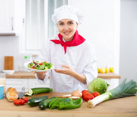 Portrait of positive woman chef presenting salad