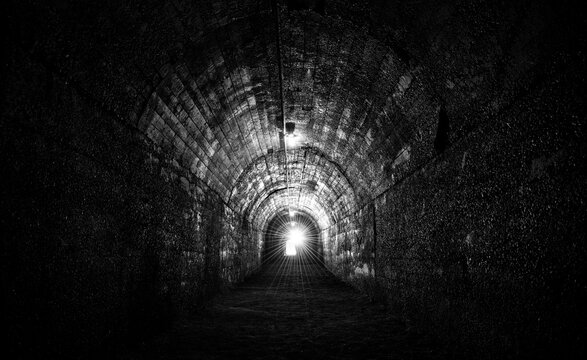 Fototapeta Historic bunker tunnel from world war 2 built with reinforced concrete now is a scary lost place in the dark with stalactites, old light bulbs, wet walls, spooky atmosphere. Black and white vintage.