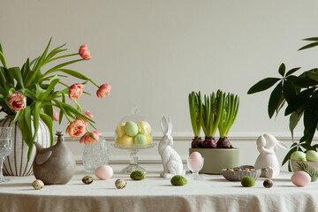 Interior design of easter dining room with colorful easter eggs, white hare sculptures, vase with...