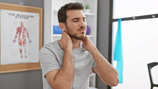 A bearded man experiencing neck pain in a modern physiotherapy clinic.