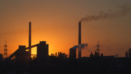 Fototapeta na wymiar Smoke from pipes of metallurgical plant against the sky at sunrise